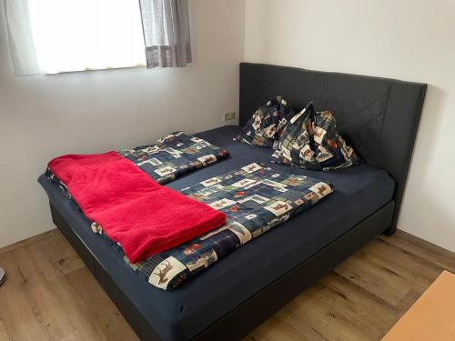 uma cama com um cobertor vermelho e almofadas em Ferienwohnung in ruhiger Lage in Bischofshofen em Bischofshofen