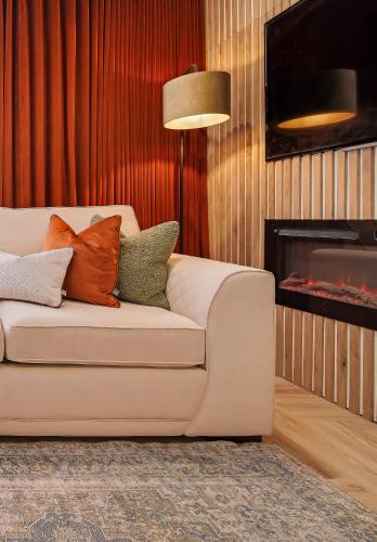 a living room with a white couch and a fireplace at The Burrow in Sion Mills