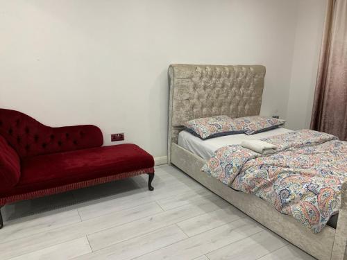 a bedroom with a bed and a red couch at Inviting 2-Bed fully Furnished House-High Wycombe in High Wycombe