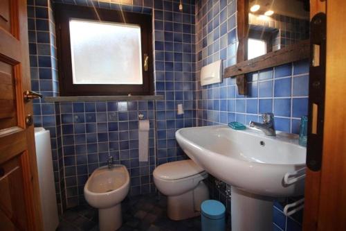 W wyłożonej niebieskimi kafelkami łazience znajduje się umywalka i toaleta. w obiekcie Baita Plagnol Sestriere Ski Slopes w mieście Sestriere