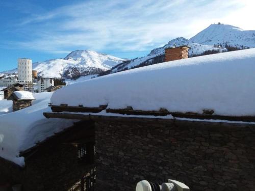 a snow covered roof of a building with mountains in the background at Baita Plagnol Sestriere Ski Slopes in Sestriere