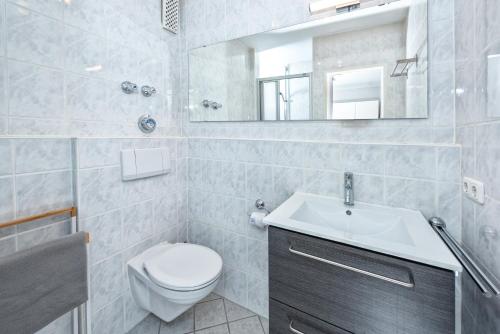 ein Badezimmer mit einem WC, einem Waschbecken und einem Spiegel in der Unterkunft Alpenglöckchen Zentral in Oberstaufen