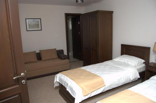 a hotel room with two beds and a couch at Complex Parc Pini Moinesti in Moineşti