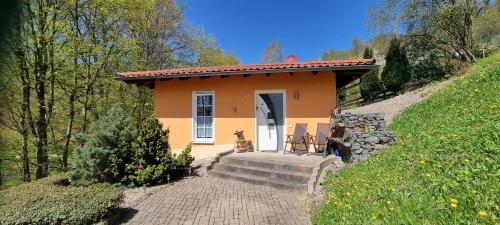 una pequeña casa naranja con dos sillas delante en Ferienhaus - Bungalow en Sonneberg