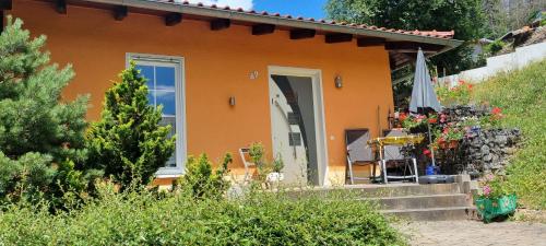 una pequeña casa naranja con porche y escaleras en Ferienhaus - Bungalow en Sonneberg