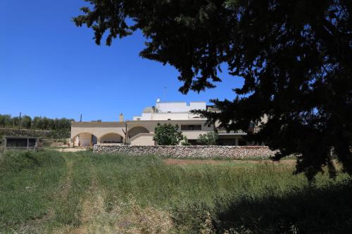 a building with a stone wall in front of a field at La Valle delle Rose in Massafra
