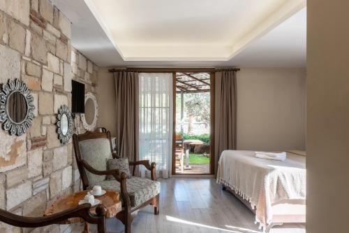 1 dormitorio con cama y pared de piedra en Espira by Antioch Hotel, en Urla
