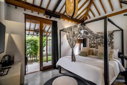a bedroom with a bed with a canopy at Bloom Resort Bali by BaliSuperHost in Canggu