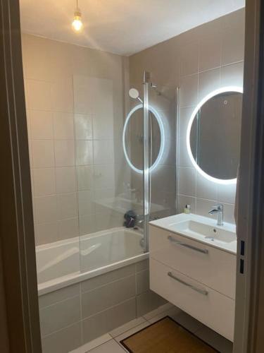 une salle de bain avec une baignoire, un lavabo et un miroir dans l'établissement Appartement de 75m2, à Gap