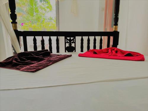 ein Bett mit zwei roten Handtüchern darüber in der Unterkunft La Villa in Unawatuna
