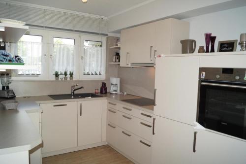 a white kitchen with white cabinets and a sink at Ferienwohnung Scheid in Scheid