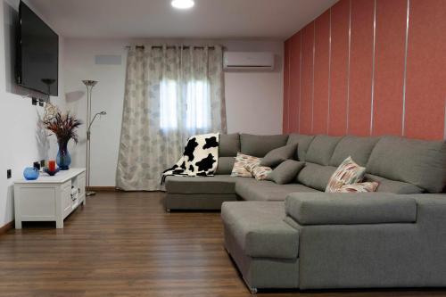 Sala de estar con sofá gris y TV en Casa Milagrito Gran Canaria en Vega de San Mateo