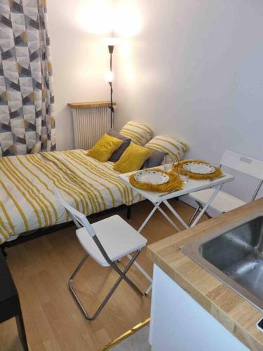 une petite pièce avec un lit, une table et des chaises dans l'établissement Mignonnette, à Paris