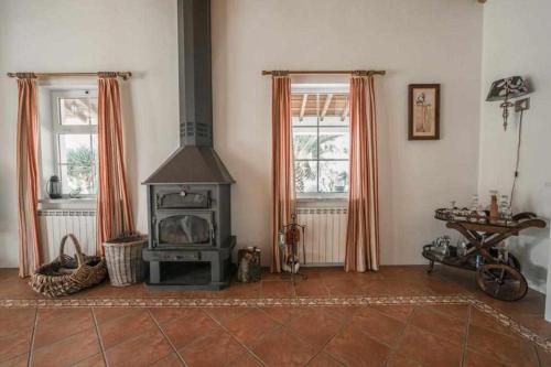 a living room with a stove and two windows at Outeiro do Álamo by Portus Alacer in Cabeço de Vide