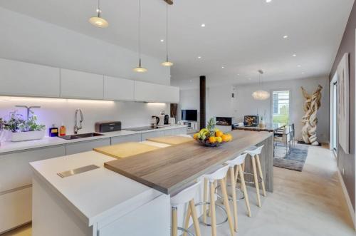 eine Küche mit weißen Schränken und eine große Insel mit Barhockern in der Unterkunft Olympic Games - Exclusive House in Villennes-sur-Seine