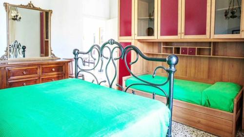 a bedroom with a green bed and a mirror at Villino Mirella a Marina di Cecina in Marina di Cecina