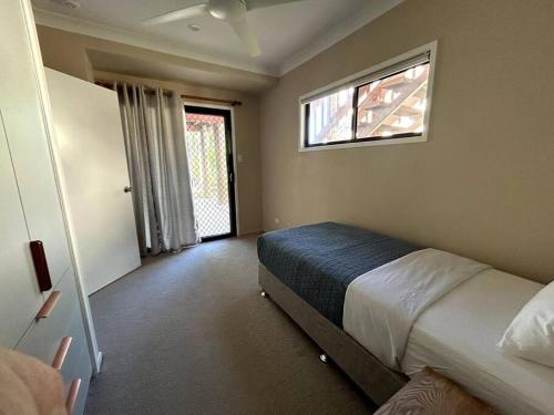 een slaapkamer met een bed en een raam bij Beachside Modern Cedar Home in Emu Park