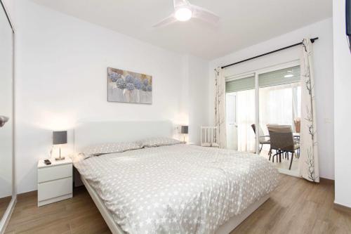 a white bedroom with a bed and a table and chairs at Ronda 3 con enorme terraza soleada in Fuengirola