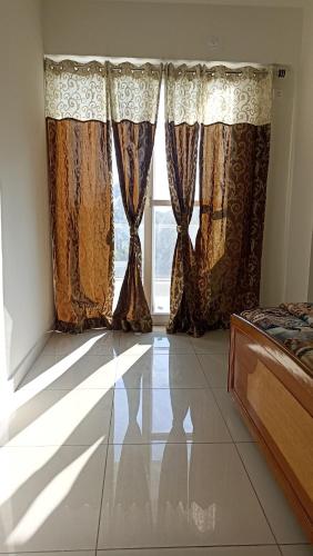 a bedroom with curtains and a large window at Blue heron homestay in Dehradun