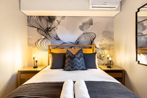 a bedroom with a large bed with a painting on the wall at The Tyne Luxury Apartments in Durban