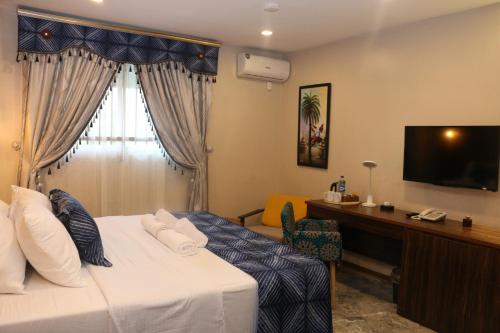 Habitación de hotel con cama, escritorio y TV. en Saire Hotels Ibadan en Ibadán
