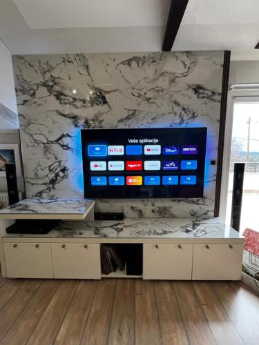a living room with a large television on a wall at Guest house Klara in Solin
