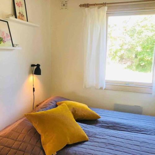 a bedroom with a bed with yellow pillows and a window at COZY HOLIDAY HOME by the sea in Yderby