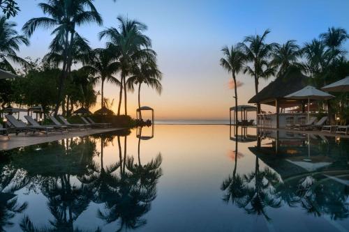 a pool at a resort with palm trees and the ocean at Hilton Mauritius Resort & Spa in Flic-en-Flac