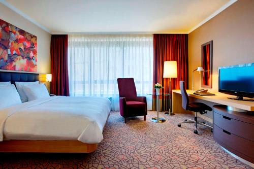 a hotel room with a bed and a desk and a television at Hilton Mainz in Mainz