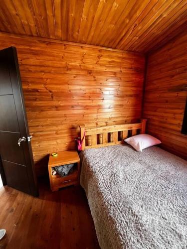 a bedroom with a bed and a wooden wall at Villa San Jerónimo in Tota