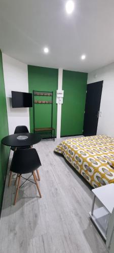 Schlafzimmer mit einem Bett, einem Tisch und Stühlen in der Unterkunft Studio Aloe tout confort rénové in Saint-Quentin