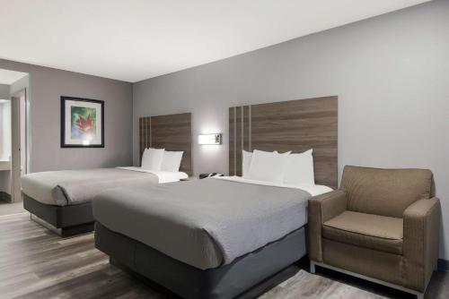ein Hotelzimmer mit 2 Betten und einem Stuhl in der Unterkunft Quality Inn near Casinos and Convention Center in Bossier City