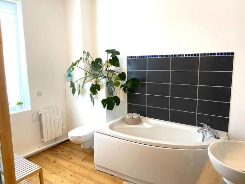 een badkamer met een wit bad, een toilet en een plant bij Maison LILLE 6 personnes avec Jardin in Lille
