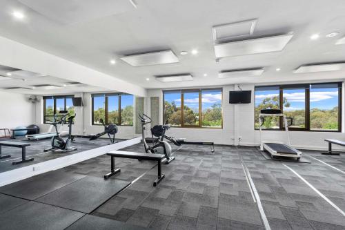 a gym with treadmills and elliptical machines and windows at Econo Lodge North Adelaide in Adelaide