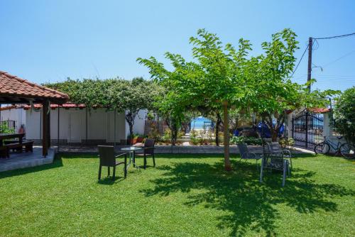 a yard with chairs and a table and a tree at Sophia houses by the sea in Nea Kalikratia