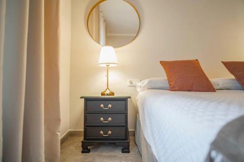 a bedroom with a bed and a lamp and a mirror at La Sultana de Vejer in Vejer de la Frontera