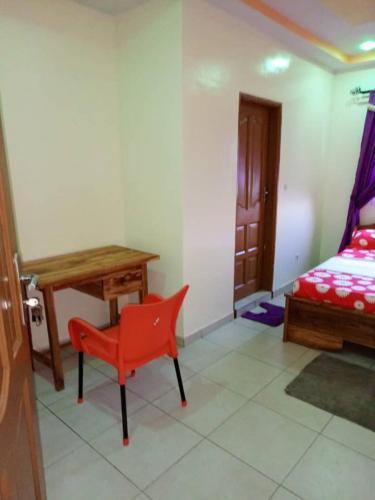 Habitación con escritorio, silla roja y cama. en Appartement Aéroport 2, en Lomé