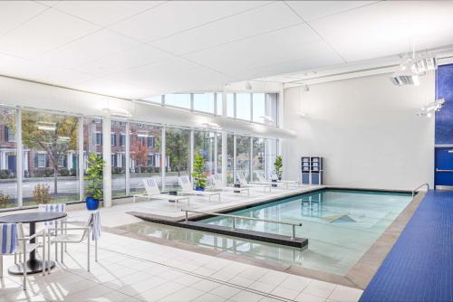 a swimming pool in a building with tables and chairs at Hampton Inn & Suites Rochester Downtown in Rochester