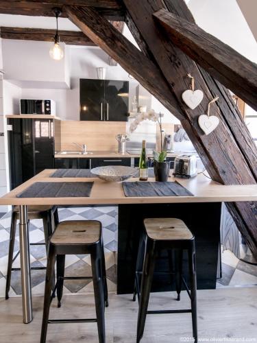 een keuken met een grote houten tafel met 2 krukken bij Gîte Au Coeur De Ribeauvillé in Ribeauvillé