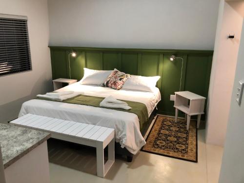 a bedroom with a bed with a green headboard at Modern Bush Living in Marloth Park
