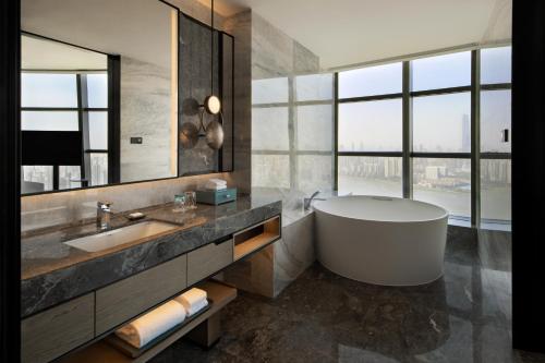 a bathroom with a tub and a large window at Wuhan Marriott Hotel Wuchang in Wuhan