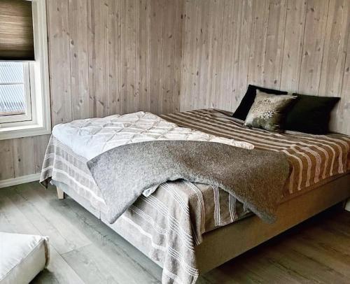 a bed in a bedroom with a wooden wall at Handelsmannens hus ved Otnesbrygga, Valsøyfjord in Otnes