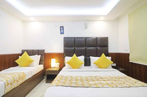 a hotel room with two beds with yellow pillows at Hotel Amara Inn - Near Delhi Airport in New Delhi