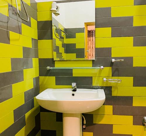 un bagno giallo e nero con lavandino e specchio di Happy Resort Yala a Tissamaharama
