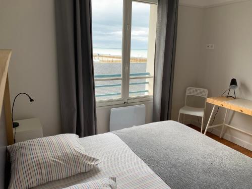 a bedroom with a bed and a view of the ocean at Le Continental in Cayeux-sur-Mer