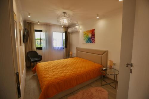 a bedroom with an orange bed and a chandelier at Apartments Panorama in Veliko Tŭrnovo