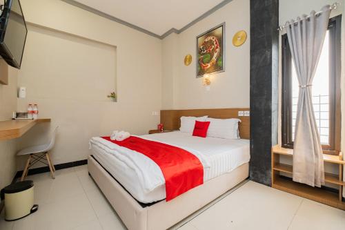 een slaapkamer met een bed met een rode deken bij RedDoorz near Kampung Inggris Pare in Pare