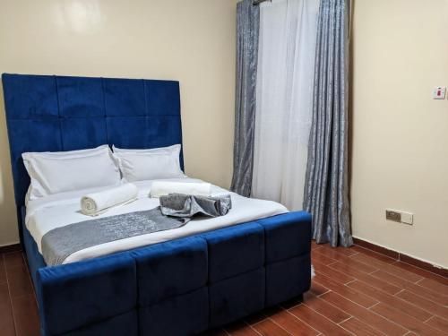 a large bed with a blue headboard in a room at bliss Haven spaces kileleshwa 2bedroom in Nairobi