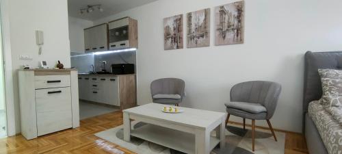 ein Wohnzimmer mit einem Tisch und 2 Stühlen sowie eine Küche in der Unterkunft Apartman Ema in Valjevo