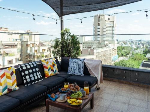 eine Couch auf einem Balkon mit Tisch mit Essen drauf in der Unterkunft Wilson Old City Roof Top in Bukarest